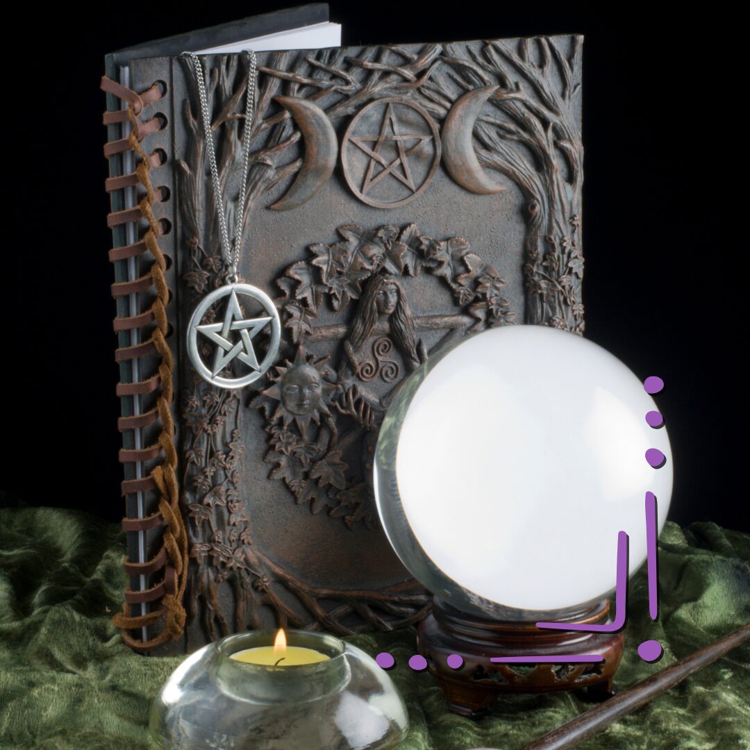 a crystal ball in front of a black journal embossed with a triple moon and a pentacle. A necklace with a silver pentacle pendant hangs over the book.