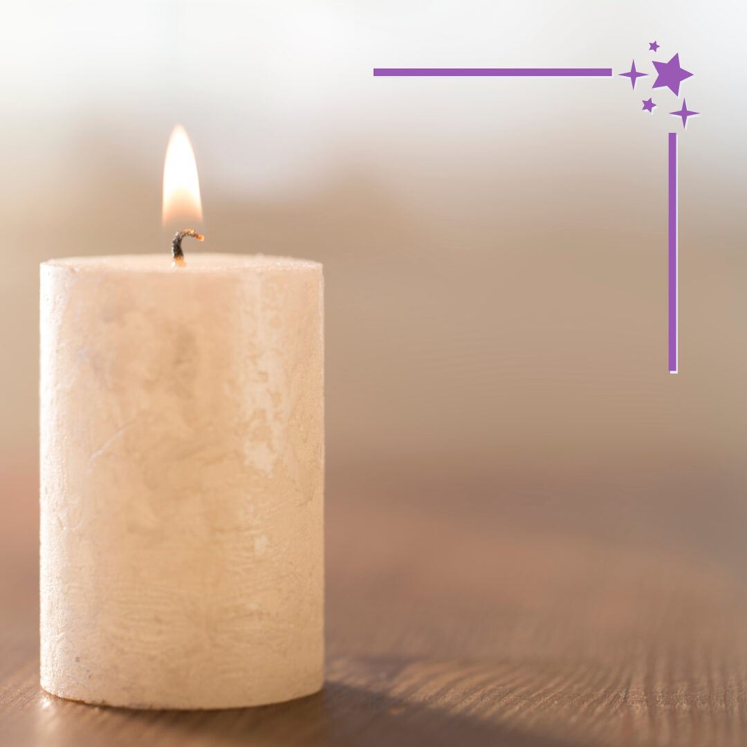 a single lit white pillar candle on a wooden surface