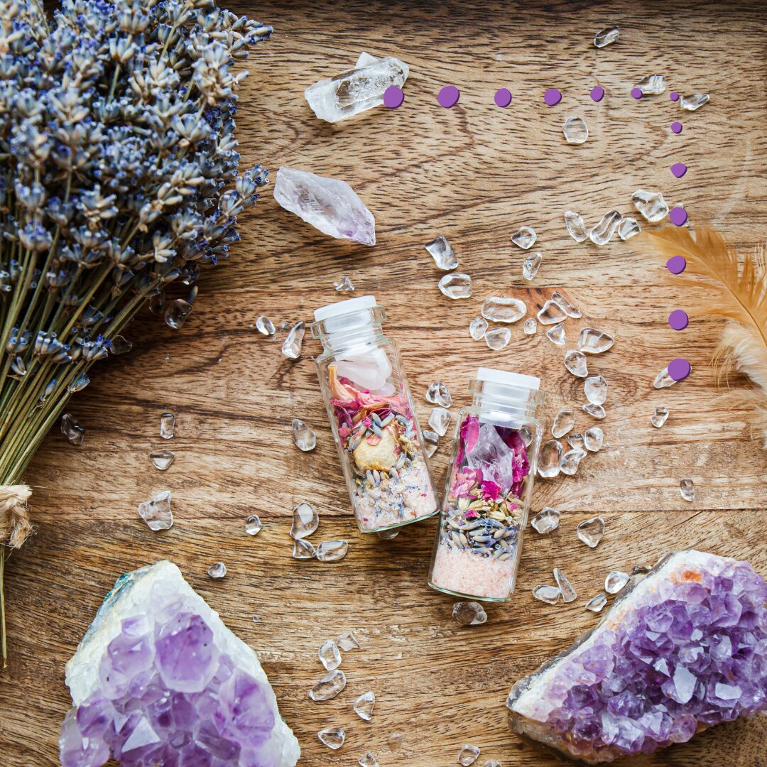 spell jars on a wooden surface, with quartz, amethyst, a feather, and lavender surrounding them