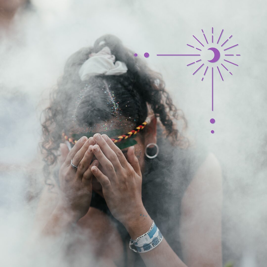 a person wreathed in smoke, hands covering their face