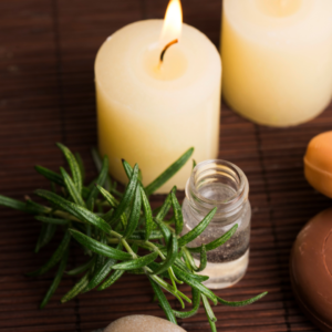 rosemary and white candles with a vial of a clear liquid