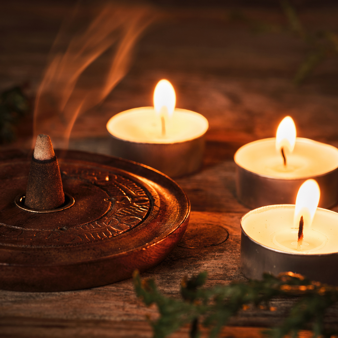 an incense cone burning, with three tealights next to it