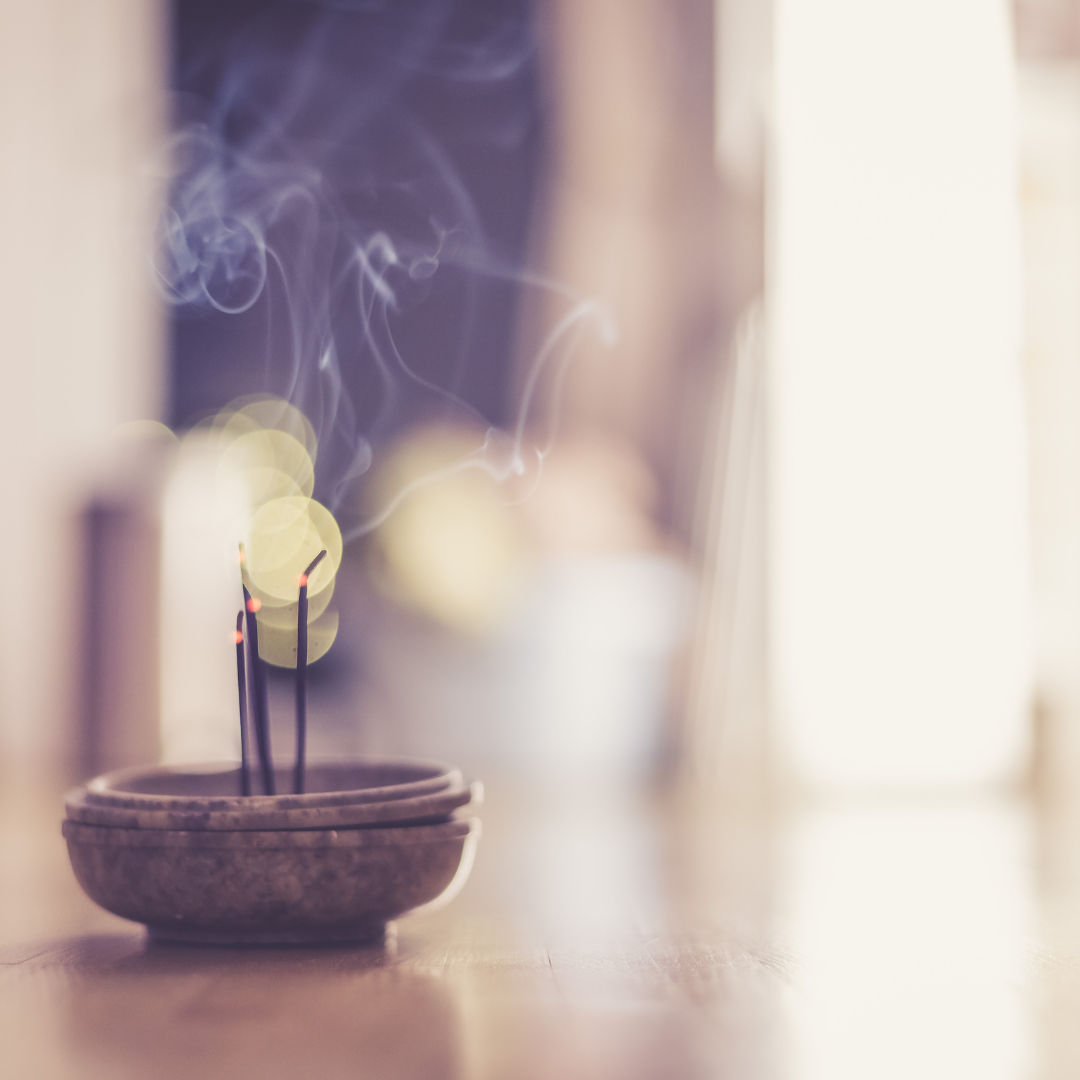 a dish with three sticks of incense burn.