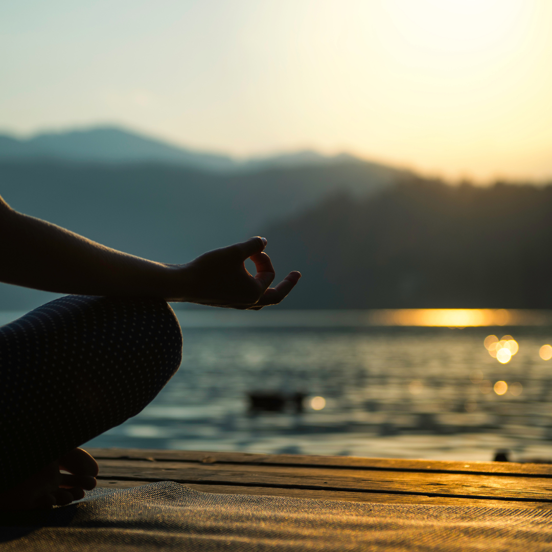 someone sitting on a dock at sunrise, meditating